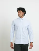 Camisa de manga larga con estampado de rayas verticales finas en color azul y blanco. Presenta cuello button-down, cierre frontal con botones nacarados y un bolsillo en el pecho.