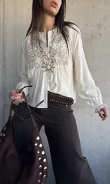 Camisa de lino color natural, con calce relajado, mangas largas amplias con puños fruncidos y delicado bordado geométrico en el frente.