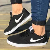 Championes Nike SB Check Solar Canvas de corte bajo, confeccionados en lona resistente de color negro. Presentan el icónico logo Swoosh en contraste blanco en los laterales y una suela de goma vulcanizada blanca que proporciona excelente agarre y durabilidad.