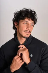 Buzo de cuello alto con cierre frontal parcial, manga larga y puños acanalados. Presenta un diseño liso en color negro con el logo de la marca bordado en el pecho.
