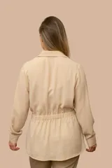 Camisa de seda color celeste, con cuello camisero, mangas largas y lazo ajustable en la cintura que genera un efecto fruncido.