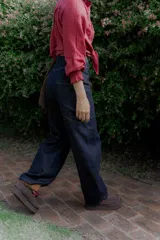 Jean de corte wide leg y tiro alto, confeccionado en denim de color azul oscuro. Presenta costuras decorativas visibles en los laterales y un diseño de pierna amplia.