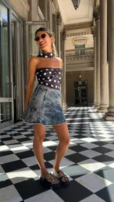 Falda corta de denim con lavado ácido (acid wash) y ruedo desflecado. Presenta un corte acampanado y cierre metálico en el costado.