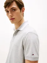 Chomba gris de corte regular confeccionada en tejido interlock de algodón suave. Cuenta con cuello de chomba, billetera de dos botones, raya a contraste en el cuello y logo del monotipo Hilfiger bordado en el pecho.