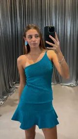 Vestido corto turquesa brillante, de un solo hombro, con tirante fino y falda con volado en el ruedo.