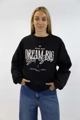 Buzo negro de cuello redondo y mangas largas, con estampa frontal en color blanco con la leyenda "DREAM BIG Start Small" y detalles de texto.