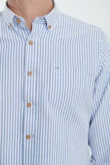 Camisa de manga larga con estampado de rayas verticales finas en tonos gris y blanco. Presenta cuello button-down, bolsillo frontal en el pecho y botones de madera.