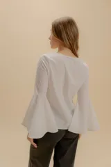 Blusa blanca de algodón bordado con escote en V y mangas amplias acampanadas con detalle de calado.