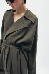 Chaqueta fluida de Zara, con cuello solapa, manga larga ajustable con trabilla y botón, y cinturón del mismo tejido con lazada. Presenta un diseño de corte recto y forro interior a tono.