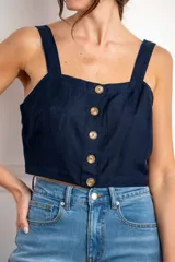 Top corto color azul marino con escote cuadrado y tirantes anchos. Presenta una hilera de botones marrones en el frente.