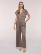 Enterito largo de lino marrón, con escote en V cruzado, mangas cortas japonesas y detalle de bordado floral en el pecho. Cuenta con cintura entallada con cinto desmontable con hebilla metálica, pantalón de pierna ancha con bolsillos y pinzas frontales.