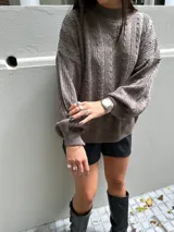 Sweater marrón tejido con diseño de ochos y cuello alto.