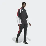 Pantalón de entrenamiento Adidas Tiro 26 Competition, de corte ajustado y color negro con las icónicas tres tiras laterales en color rojo. Presenta un diseño con textura en la parte inferior de las piernas y el logo de la marca en el muslo.