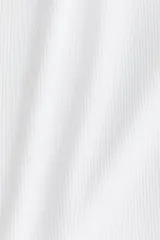 Musculosa blanca de punto acanalado, con escote en U pronunciado tanto en el frente como en la espalda y tirantes finos.