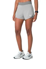 Short deportivo Fila de doble capa para mujer, en color gris. Cuenta con una capa exterior ligera y holgada, y una capa interior ajustada de tipo calza corta, con cintura elástica ancha y logo de la marca estampado en el lateral.