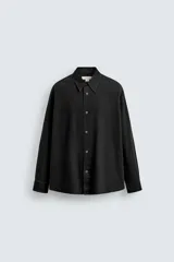 Camisa de corte relajado confeccionada en algodón con efecto lavado. Presenta cuello solapa, manga larga y cierre frontal con botones a presión metálicos.