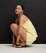 Short de sastrería color amarillo claro, de tiro alto con cintura elástica y cierre tradicional. Presenta frisos verticales en la parte delantera.