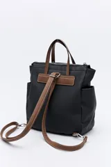 Mochila negra de poliéster texturizado con superficie acanalada. Cuenta con asas superiores marrones, tiras regulables para la espalda, bolsillo frontal con cierre metálico, compartimentos laterales y un interior amplio.