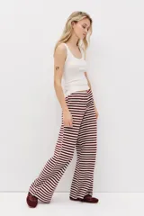 Pantalón de punto suave, de piernas amplias y corte holgado, con diseño a rayas horizontales en color bordó y blanco. Cuenta con cintura elástica y cordón ajustable.