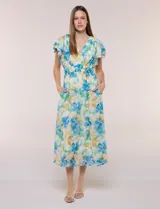 Vestido midi de gasa con estampado floral en tonos azules, verdes y amarillos, escote en V cruzado, mangas cortas con volados, cintura elastizada y bolsillos laterales.