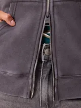 Canguro con cierre frontal y capucha, color gris con efecto desgastado. Presenta bolsillos laterales y logo bordado en el pecho.