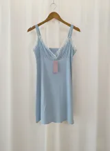 Camisón maternal de algodón color celeste, con escote en V y delicados detalles de puntilla blanca en el borde. Presenta breteles anchos y un diseño cómodo y holgado, ideal para el embarazo y la lactancia.