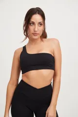 Top deportivo negro asimétrico con un solo tirante ancho, confeccionado en tejido Compress con protección UV50+ y fibras biodegradables.