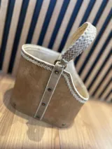 Cesto organizador de cuero color marrón claro con manija superior trenzada y detalles de costura en color crudo.