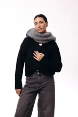 Saco de tejido de punto grueso en color negro, con cuello redondo y cierre frontal mediante tres botones metálicos grandes de acabado texturizado. Presenta bolsillos delanteros y mangas largas con puños ajustados.