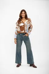 Saco de punto con escote en V y cierre frontal de botones. Presenta un diseño estampado con formas abstractas en tonos marrón, blanco y celeste.