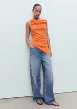 Top de punto fino color naranja, sin mangas, con cuello drapeado y bajo asimétrico.