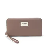 Billetera larga con cierre perimetral, confeccionada en material sintético texturizado color mostaza. Cuenta con correa de mano extraíble y placa metálica con logo de la marca en el frente.