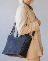 Bolso tipo shopper de gamuza color negro, forrado en su interior. Cuenta con asas de mano y una correa larga desmontable para llevar al hombro o cruzado.