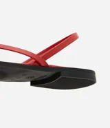 Sandalias planas rojas con diseño de dedo, tiras finas y aplique metalizado decorativo.