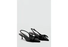 Zapato de tacón tipo slingback en color negro, con diseño destalonado, puntera fina y un detalle de lazo en la parte delantera. Cuenta con tira ajustable en el talón con hebilla metálica dorada y taco fino de altura baja.