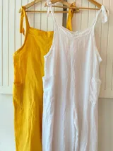 Mono de lino blanco con tirantes finos que se atan en los hombros y bolsillos laterales.
