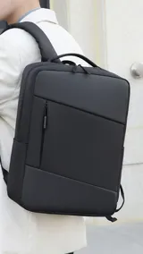 Mochila negra con bolsillo frontal con cierre, bolsillos laterales, cargador USB integrado, compartimento para laptop y asa de mano. La espalda acolchada brinda comodidad.