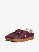 Zapatillas de corte bajo confeccionadas en piel napa brillante color bordó, con suela de goma color caramelo. Presentan insignia metálica del monograma TH en el lateral y detalle en blanco en el talón.