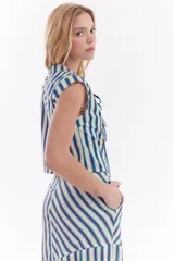 Blusa sin mangas de algodón con estampado de rayas en tonos beige, azul y rojo. Presenta diseño de inspiración oriental con cierre frontal de múltiples lazos para atar.