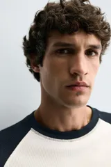 Camiseta de manga larga con estructura waffle, corte regular fit. El cuerpo es de color blanco crudo y las mangas raglán son de color azul marino. Tiene cuello redondo a contraste.