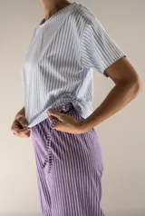 Pijama de algodón a rayas, compuesto por una remera de manga corta con cordones ajustables en los laterales y un pantalón de corte recto y holgado.