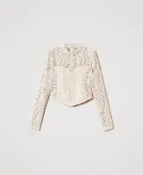 Blusa corta de encaje macramé color marfil, con cuello mandarín, mangas largas tipo guante con fruncido en las sisas y bajo asimétrico.