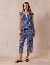 Conjunto de pijama marca René Rofé, compuesto por remera de mangas cortas con escote en V abotonado y pantalón capri con cintura elastizada. Diseño estampado con flores azules sobre fondo blanco.