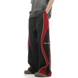 Pantalón deportivo de calce amplio y oversize, color negro con paneles laterales en rojo y vivos blancos que recorren el corte. Posee bolsillo lateral con cierre y cintura regulable.