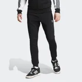 Pantalón deportivo Adidas Adicolor Classics SST negro con tres rayas blancas a los costados, corte ajustado, puños acanalados, logo del trifolio bordado en la pierna izquierda, bolsillos laterales con cierre y cintura elástica con cordón de ajuste.
