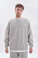 Sudadera gris claro con efecto lavado, de corte holgado y manga larga. Presenta una estampa minimalista en la espalda con el texto 'city pulse', 'street vibe' y 'subway beat'.