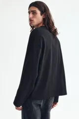 Remera de manga larga en punto pesado, color negro, con cuello redondo ribeteado, hombros caídos y bajo recto. Corte oversized para una silueta amplia y relajada.