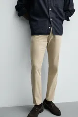 Pantalón chino de corte ajustado, color beige, con bolsillos laterales y bolsillos traseros de vivo. Cuenta con cierre frontal de cremallera y botón.