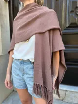 Ruana tejida en color marrón mocca, con diseño de punto liso y detalle de flecos en los extremos.