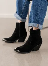 Bota corta de estilo western confeccionada en cuero vacuno negro, con puntera metálica plateada y taco cuadrado de 7 cm.